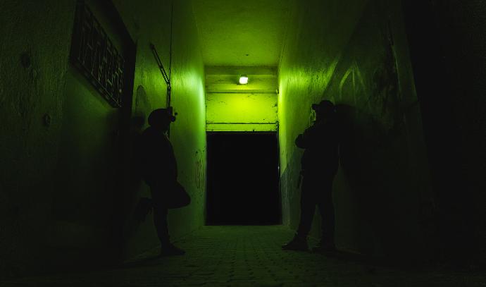 man in black jacket standing near green wall