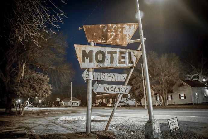 a motel sign sitting on the side of a road